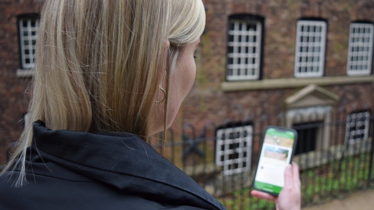 A visitor stood outside the mill at Quarry Bank looking at her mobile phone